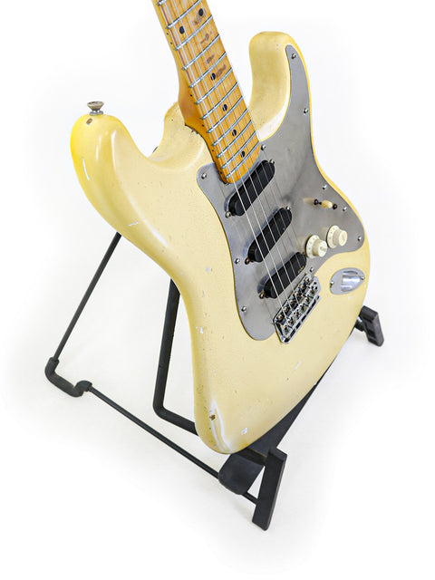 Classic yellow 1974 Fender Stratocaster guitar showcased on a stand, with a minimalist white background enhancing its beauty.