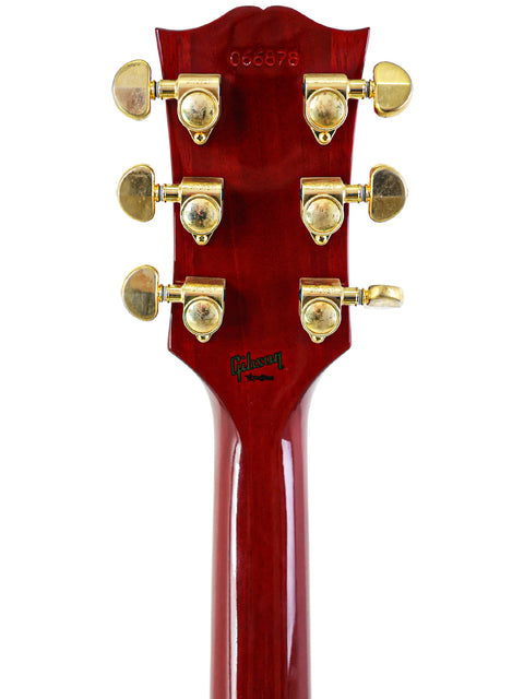 Close-up of a red guitar headstock featuring gold hardware, part of a 2006 Gibson Custom Shop '68 Reissue Les Paul Custom.