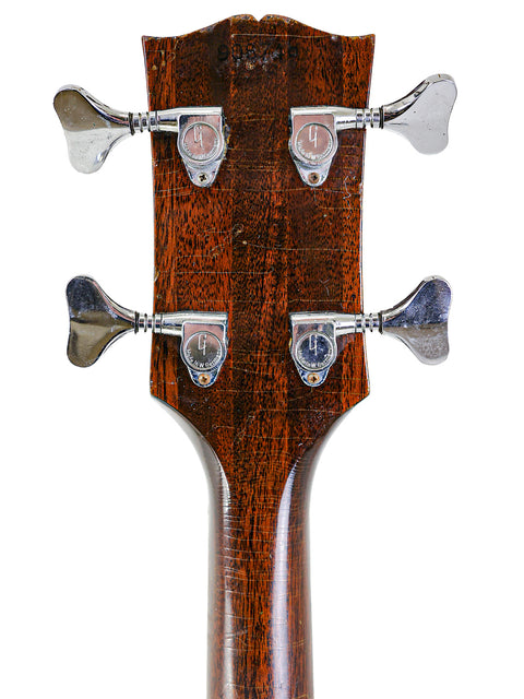 Close-up shot of a 1969 Gibson EB-1 guitar head, featuring a beautifully crafted wooden body and iconic design.