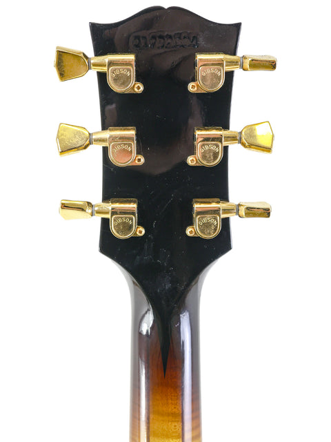 Detailed view of the headstock on a 2002 Gibson L-5 CES guitar, emphasizing the stunning gold hardware design.