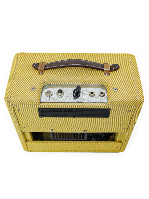 Fender Custom Shop '57 Champ Combo amplifier in yellow, elegantly encased in leather, representing vintage musical heritage.