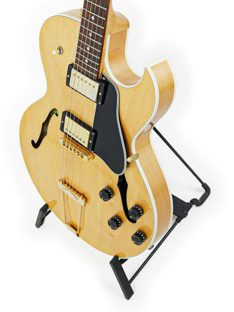 Gibson ES-135 guitar from 2002 elegantly positioned on a stand, set against a pristine white backdrop for a striking visual.
