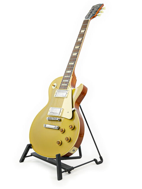 Gold Gibson Custom Shop LPR-7 1957 Les Paul Goldtop guitar displayed on a stand with a clean white backdrop.