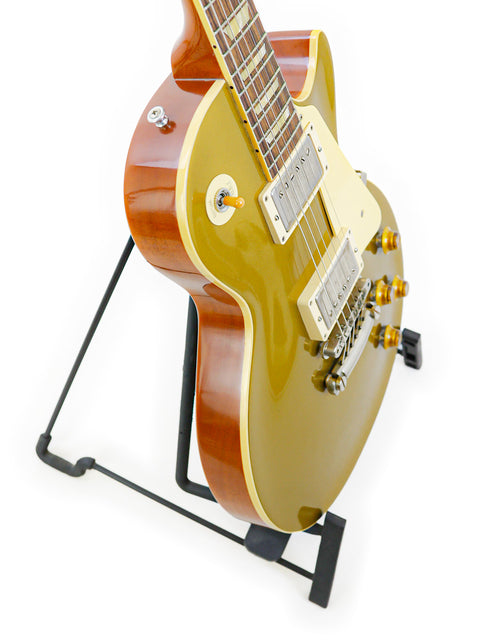 Golden electric guitar, a Gibson Custom Shop LPR-7 1957 Les Paul Goldtop Reissue, elegantly positioned on a stand.