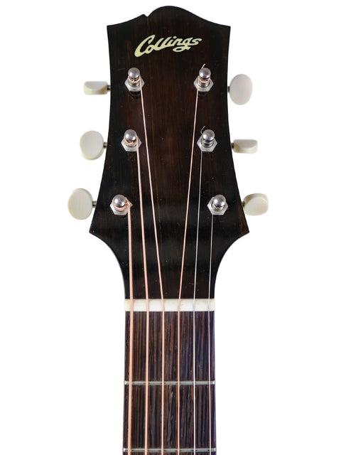 Headstock of a Collings guitar with tuning pegs and strings visible on a white background.