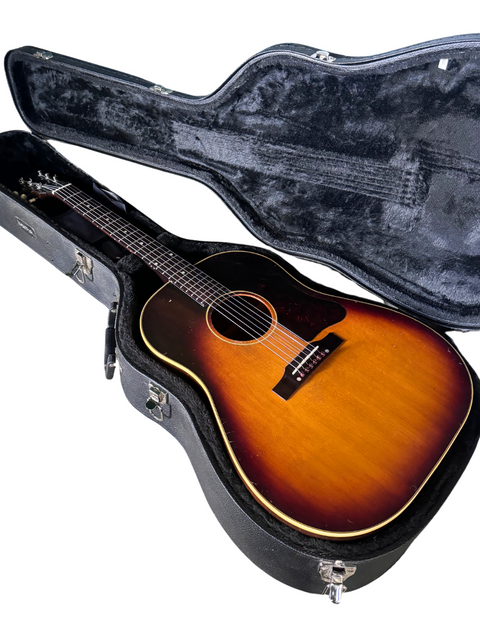 Inside a guitar case lies a vintage Gibson J-45 acoustic guitar from 1960, highlighting its rich history and elegant style.