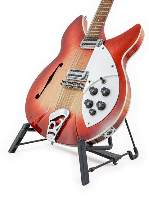 Red Rickenbacker 12-string guitar displayed on a stand with a white backdrop, showcasing its vintage design.