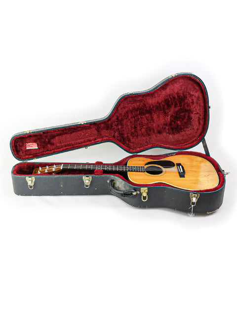 Red and black guitar case housing a 1974 Vintage Martin 000-28, reflecting its timeless craftsmanship and design.