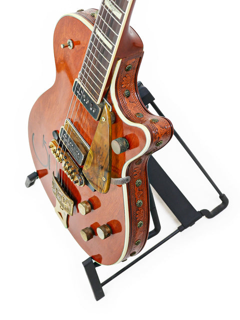 The Vintage Gretsch 6130 Roundup guitar from 1955 elegantly positioned on a stand, highlighted by a white backdrop.