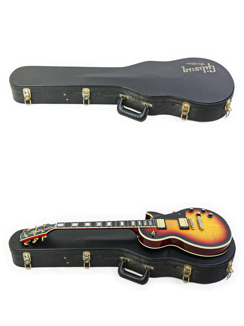 Two guitars are stored in a case, featuring a Gibson Custom Shop '68 Reissue Les Paul Custom on top, ready for transport.