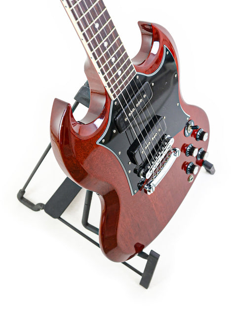 Vibrant red Gibson SG Classic guitar resting on a modern black stand, a must-have for serious guitar enthusiasts.