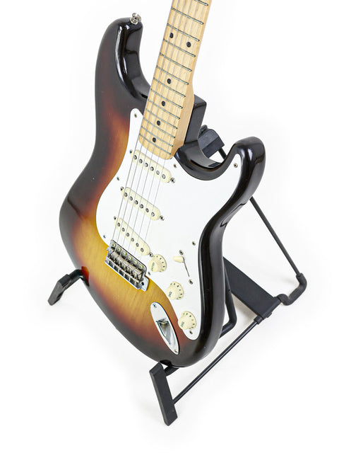 Vintage 1958 Fender Stratocaster guitar on a stand, artistically presented with a bold black background.