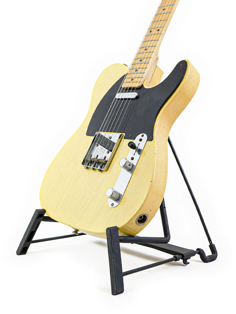 Yellow Fender Custom Shop 70th Anniversary Broadcaster guitar displayed on a stand featuring a black base.