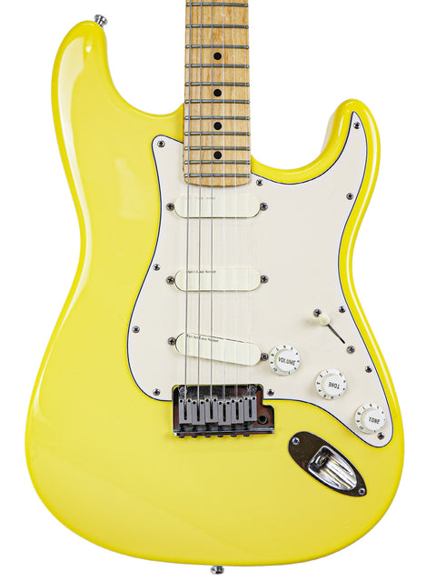 Yellow electric guitar with white pickguard and maple fretboard, isolated on a white background.