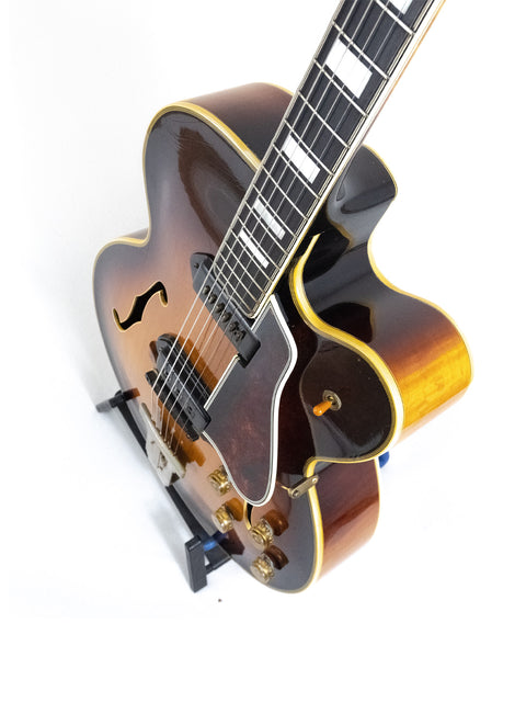 1955 Gibson L-5 CES guitar showcasing a brown body and black pick guard, equipped with Alnico pickups.