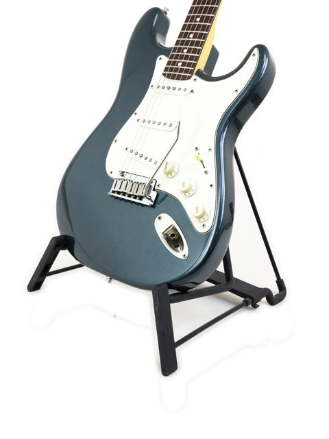 1989 Fender Strat Plus Deluxe guitar elegantly positioned on a stand with a pristine white backdrop.