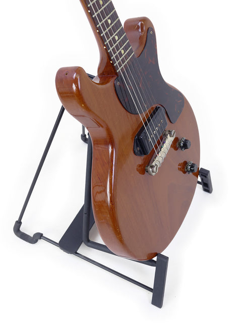 A 1959 Vintage Gibson Les Paul Jr guitar displayed on a black stand, highlighting its iconic shape and style.