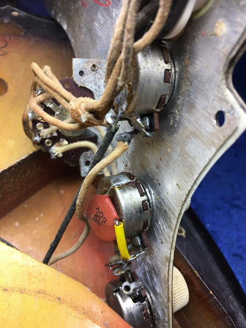 A 1964 Fiesta Red Fender L Series Stratocaster guitar with wires connected to it, showcasing its vintage design.