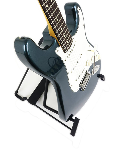 A 1989 Fender Strat Plus Deluxe guitar with a black body resting on a stand, exemplifying timeless musical artistry.
