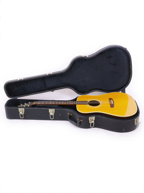 A 1989 Guild D40 guitar securely housed in a case, set against a stark white background.