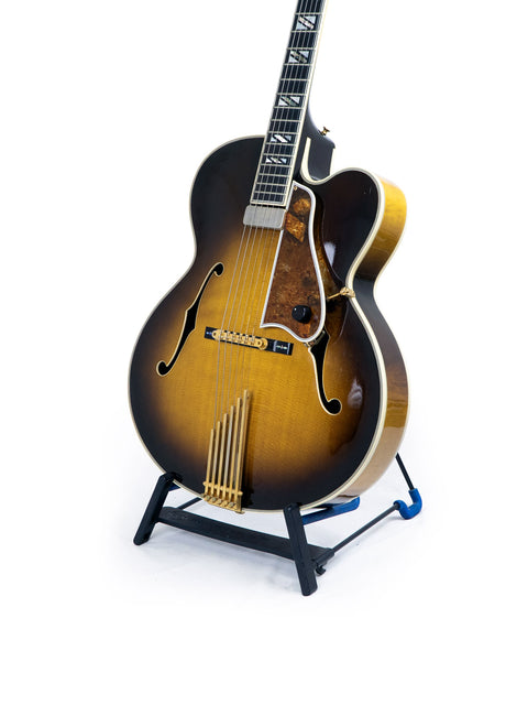 A 1997 Gibson Custom Shop Le Grand Archtop guitar stands on a display against a bright white background.