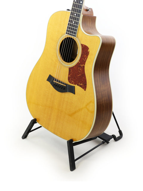 A 2011 Taylor 410CE guitar on a stand, set against a bright white background.