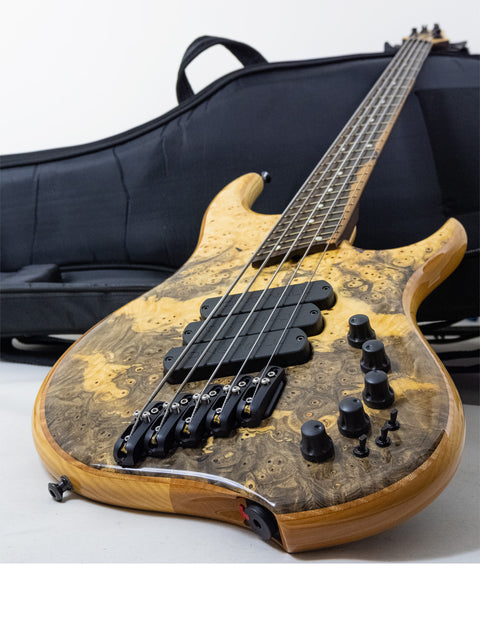 A Dingwall Z3 Buckeye Custom 5 String Bass guitar in its case, resting on a table, showcasing its elegant design.