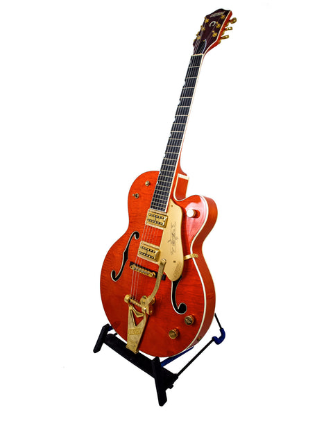 A Gretsch Chet Atkins G6120 guitar featuring a gold tone and vibrant orange body, crafted in Japan in 2011.