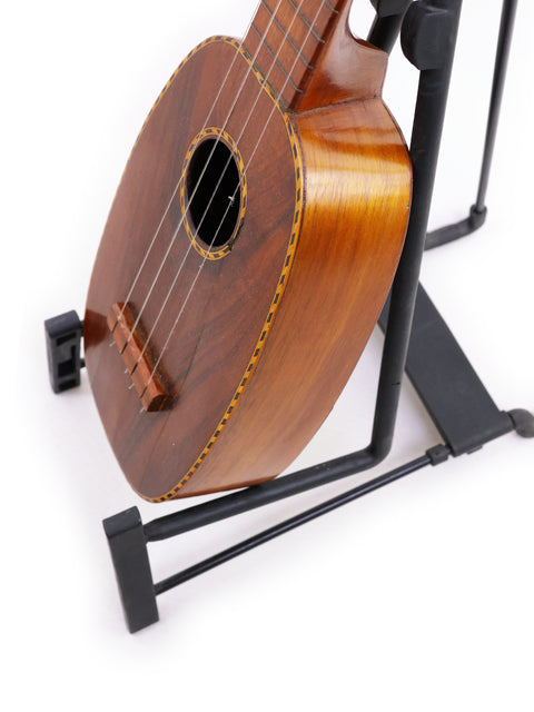 A Kamaka Pineapple Style #3 ukulele from 1928 sits on a stand, highlighting its vintage charm.