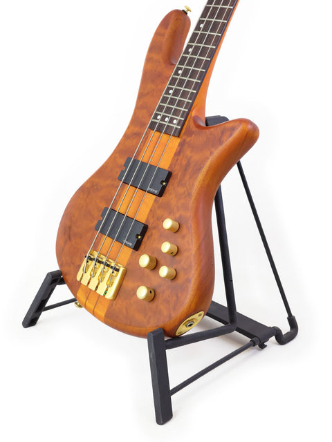 A Schecter Stiletto Studio 4 bass guitar elegantly displayed on a stand with a bright white backdrop.