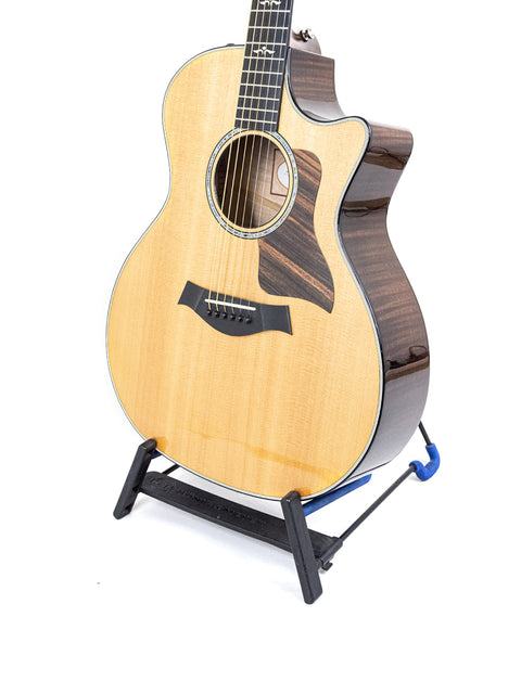 A Taylor 614ce grand acoustic guitar displayed on a stand, highlighting its beautiful finish and USA craftsmanship from 2016.