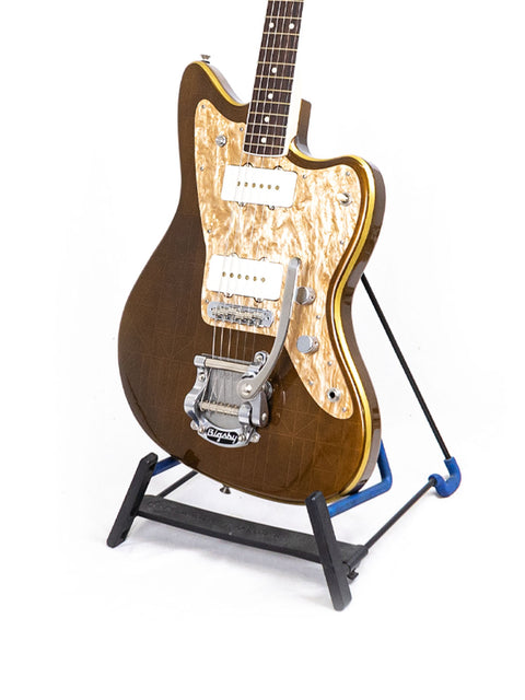 A beautiful wooden guitar, the Zachary & Mercer Mastermind “Deluxe” Offset, proudly standing on its stand.