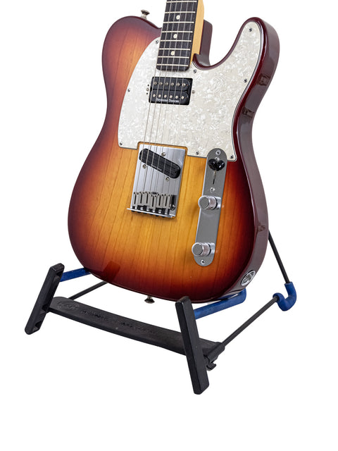 A black-based stand holding a Fender American Standard Telecaster guitar from 2002, emphasizing its classic style and quality.