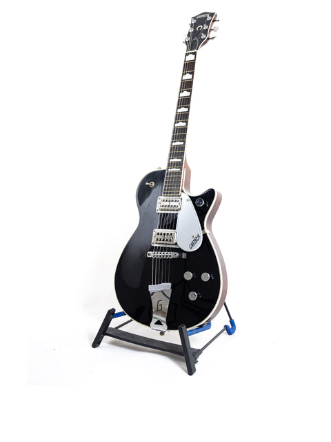 A black Gretsch Duo Jet 6128 guitar from 1989 positioned on a stand, set against a bright white background.
