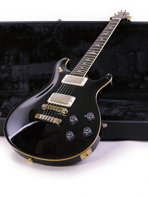 A black electric guitar, PRS McCarty 594 from USA 2016, resting in its protective case, highlighting its elegant features.
