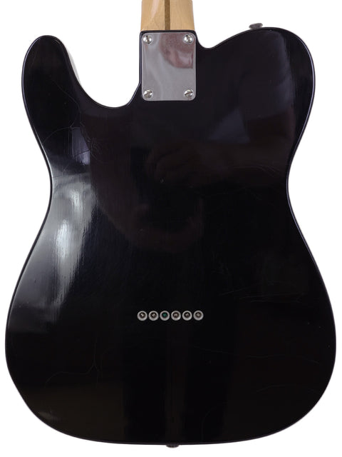 A black guitar featuring a wooden body and black pickguard, identified as a 2005 Fender Custom Shop Telecaster Thinline.