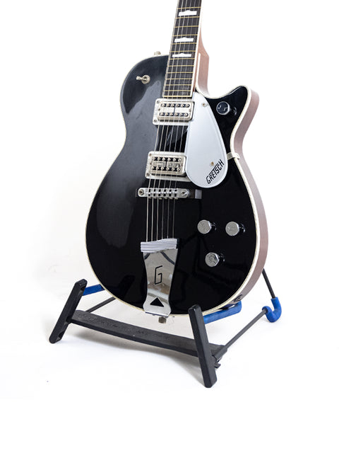A black guitar, the Gretsch Duo Jet 6128 from 1989 Japan, rests on a stand with a distinctive blue foot.