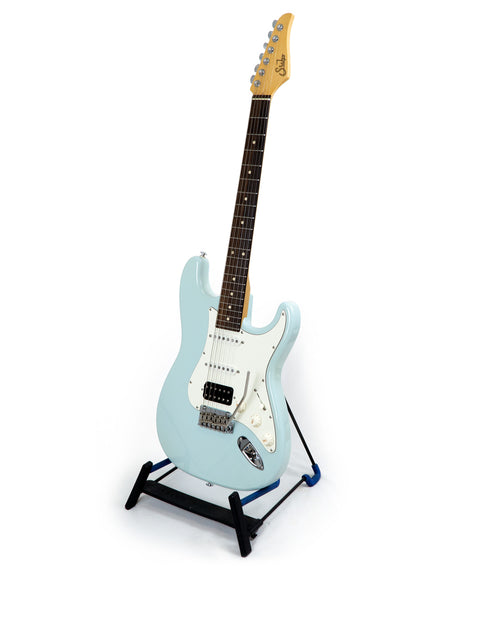 A blue electric guitar, Suhr Classic Pro model, elegantly positioned on a stand with a white background.