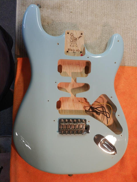 A blue electric guitar, Warmoth Strat Partscaster from 2012, featuring several missing components, awaiting a new life.