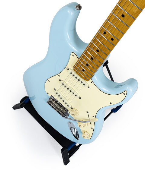 A blue electric guitar resting on a stand, showcasing the craftsmanship of a Warmoth Strat Partscaster from the USA, 2012.