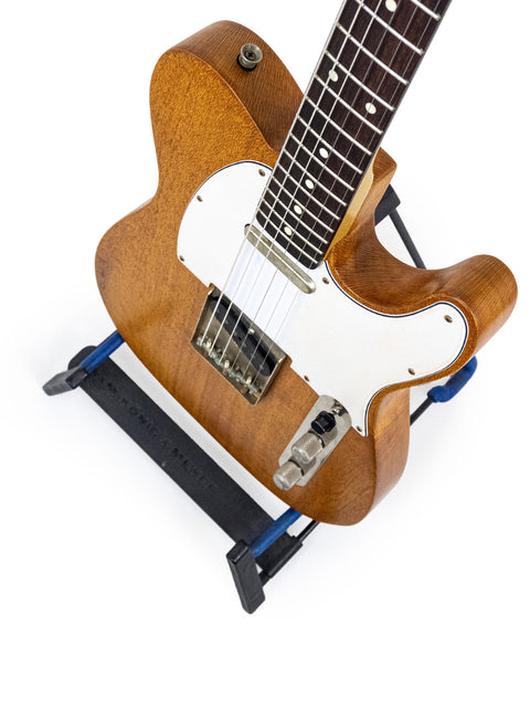 A blue stand supporting a Silky Oak Txxx Style Partscaster guitar, representing its new model from Australia, 2021.