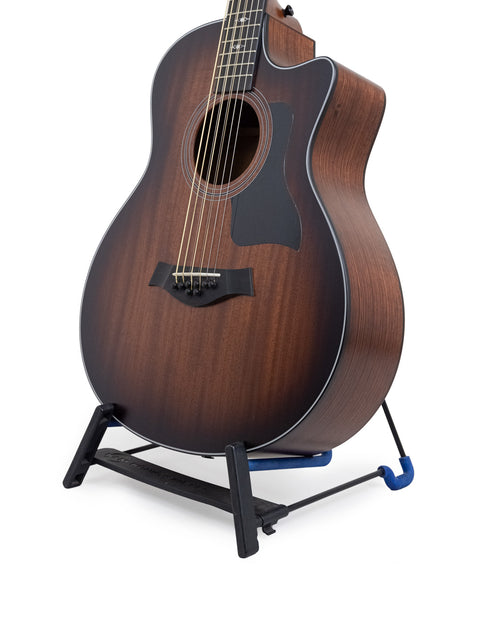 A brown Taylor 326 CE Baritone 8 LTD acoustic guitar on a stand, emphasizing its beautiful wood finish and design.