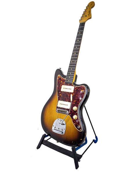 A classic 1960 Fender Jazzmaster guitar on a stand, elegantly presented with a white background, emphasizing its vintage appeal.