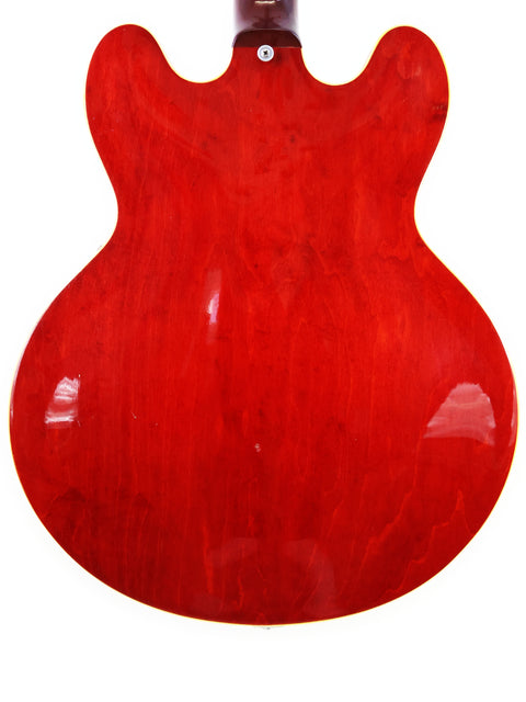 A classic 1963 Gibson ES-335 guitar, showcasing a vibrant red color with a contrasting black body and neck.
