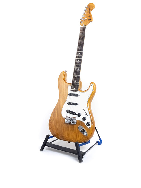 A classic 1979 Fender Stratocaster guitar on a stand, showcased against a plain white background.