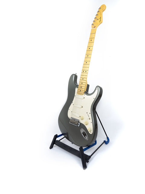 A classic Fender Eric Clapton Stratocaster guitar displayed on a stand with a bright white backdrop.