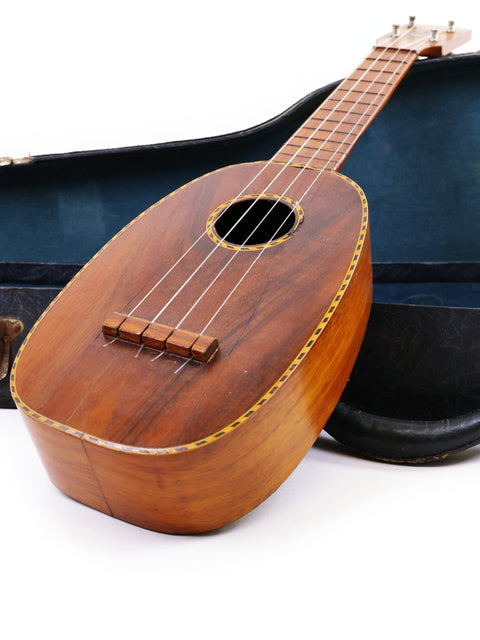 A classic Kamaka Pineapple Style #3 ukulele from 1928 nestled in its case, set on a white backdrop.