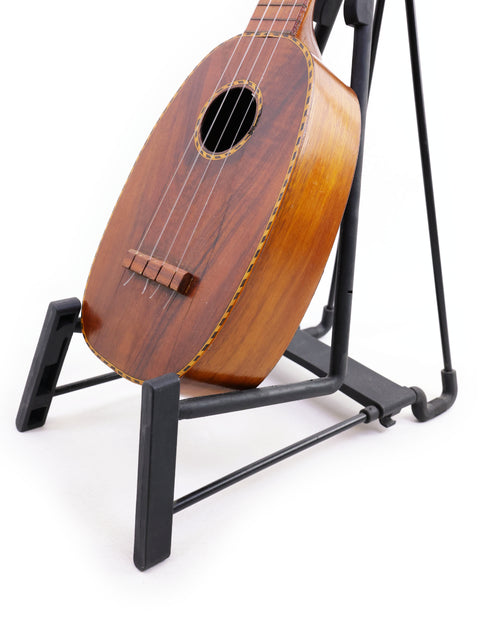 A classic Kamaka Pineapple Style #3 ukulele from 1928 sits on a stand, highlighting its vintage charm.