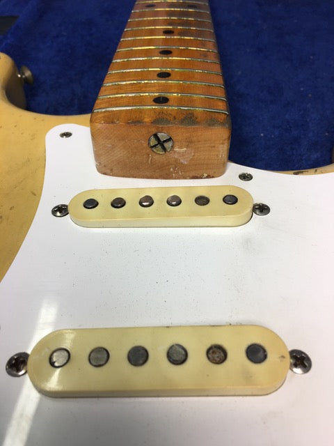 A close-up of a 1959 Fender Stratocaster guitar, emphasizing the white pick guard and the blond maple neck.