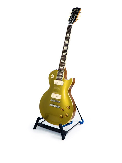 A golden guitar on a stand against a white background, showcasing the Gibson Custom Historic Limited Edition VOS LPR-6 1956 Les Paul Goldtop.